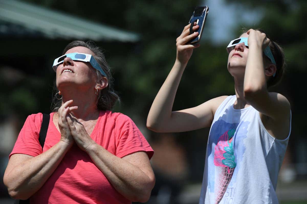 Two people viewing an eclipse wearing eclipse glasses